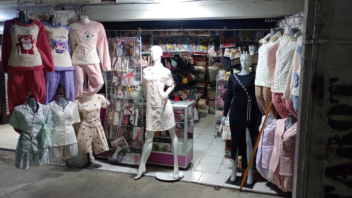 Entrada del puesto con pijamas de peluche colgadas y maniquíes al frente